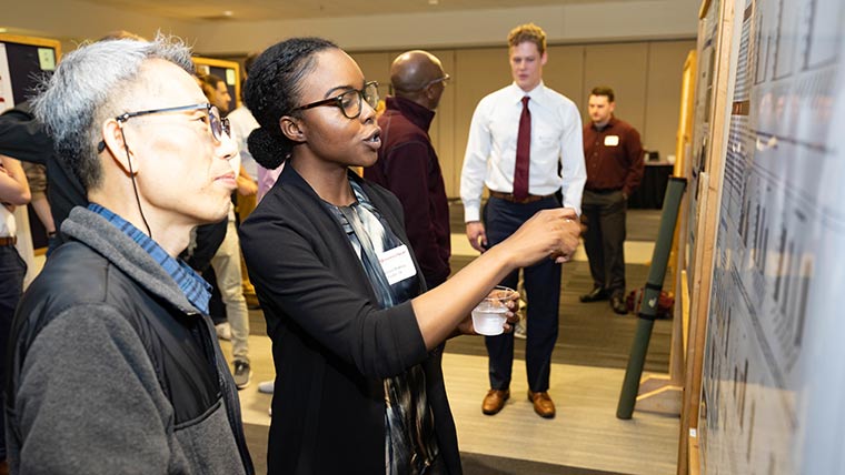 A biology student discusses her research work with CNAS professor Dr. Kyoungtae Kim during the CNAS Undergraduate Research Symposium.